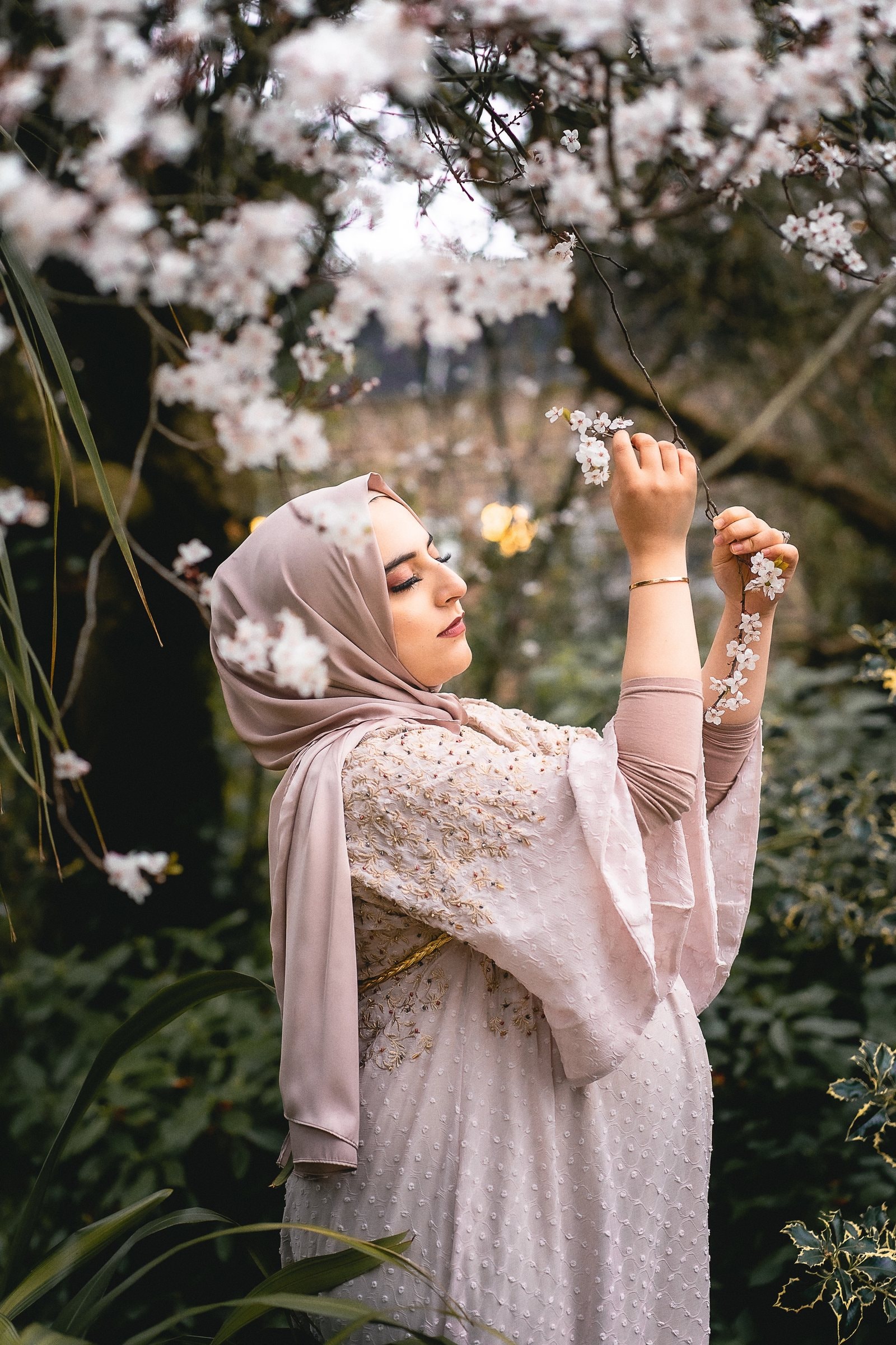 A pregnant woman standing among spring leaves