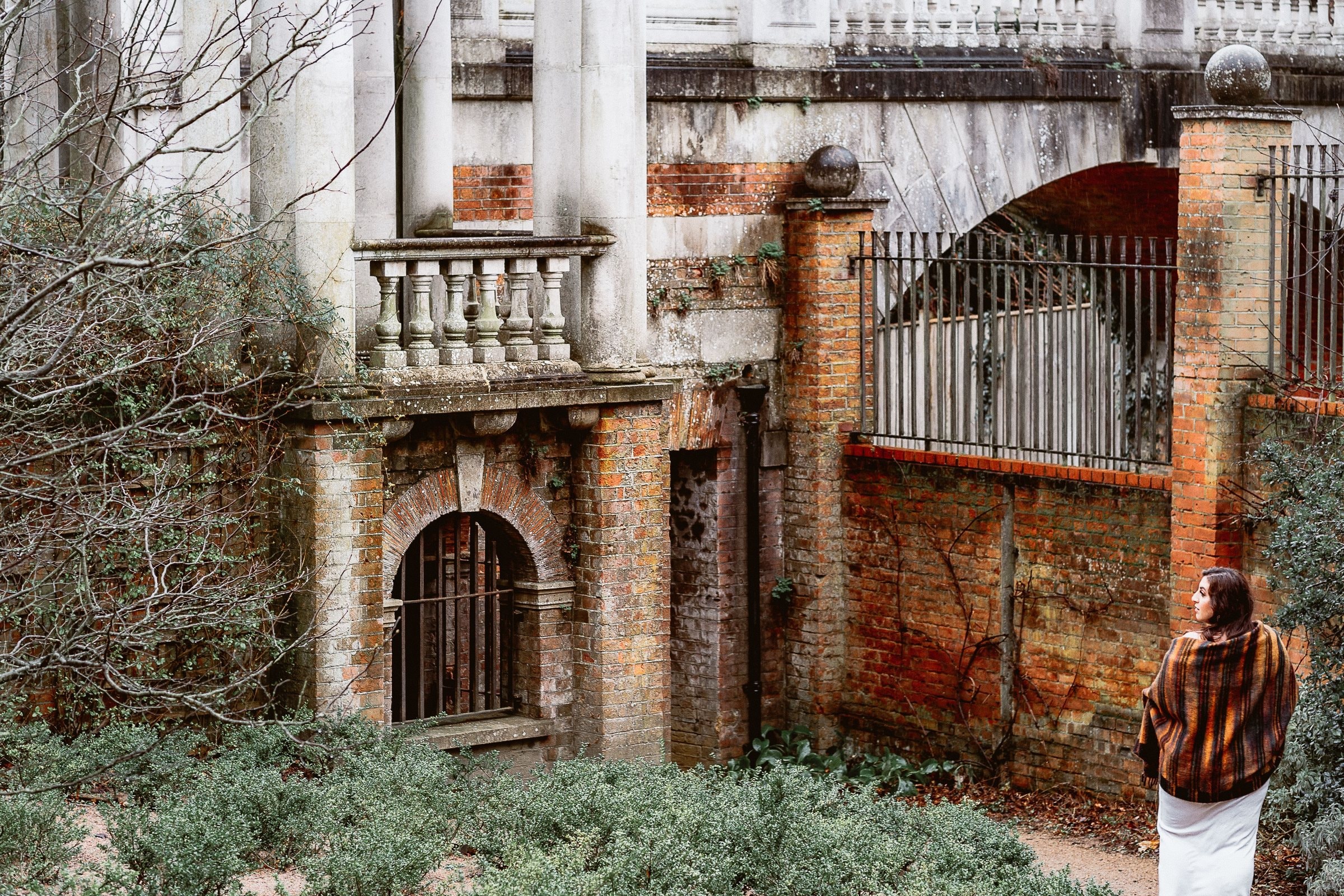 Noor standing beside a weathered garden building