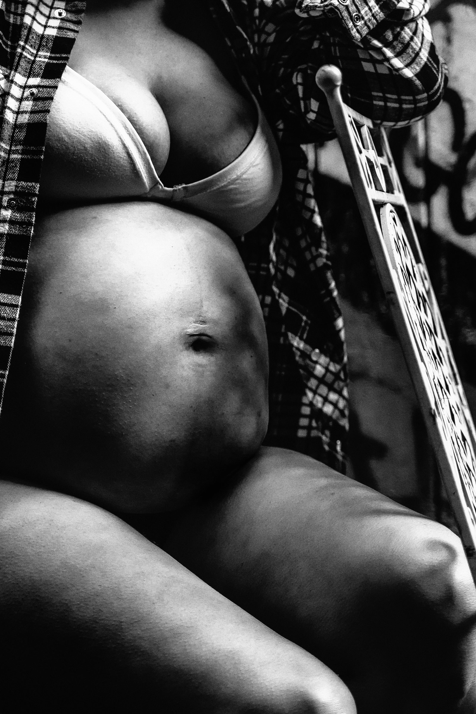 Solene seated beneath the pier in a quiet maternity portrait