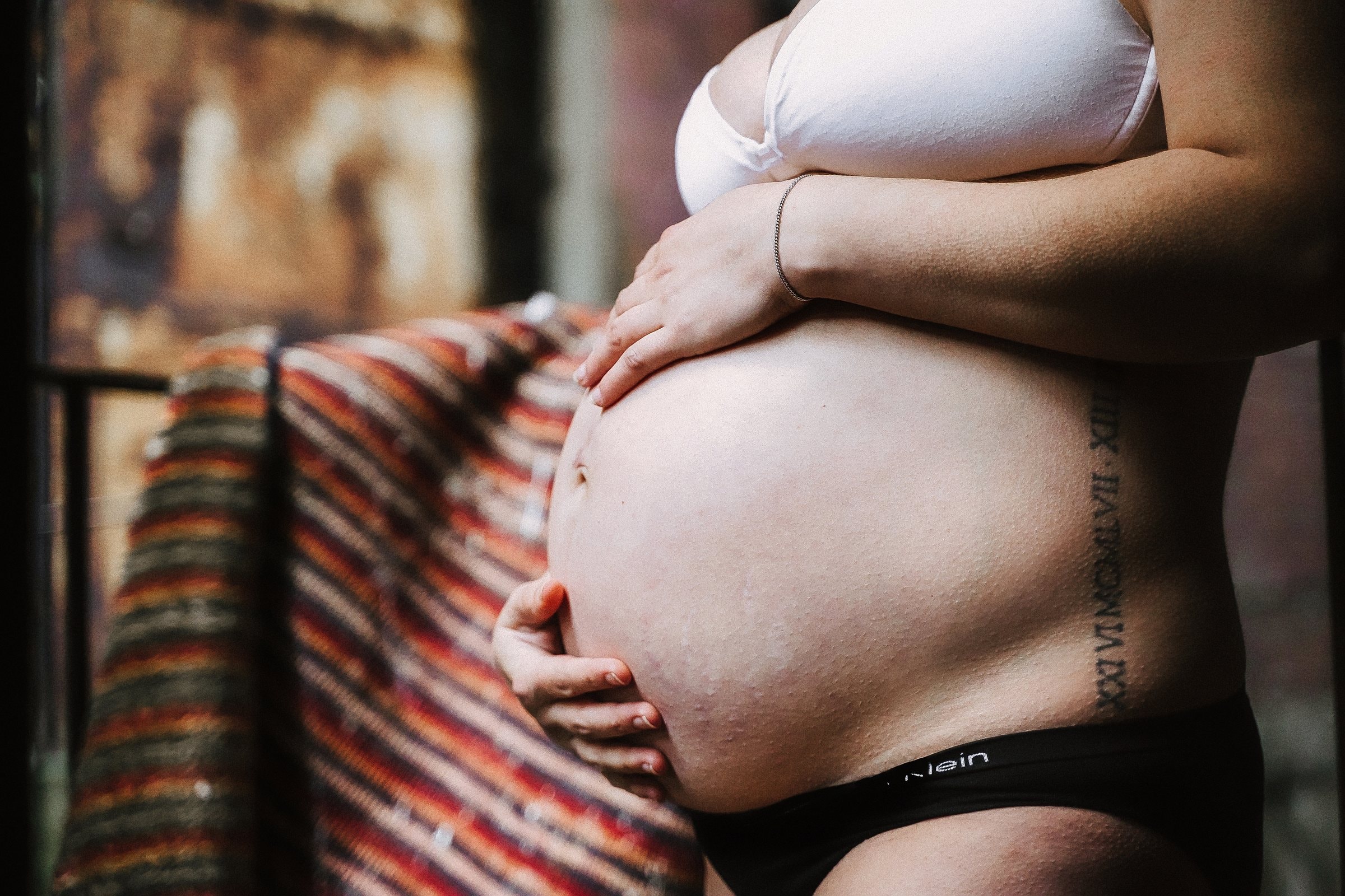 Solene holding her belly in an intimate close portrait