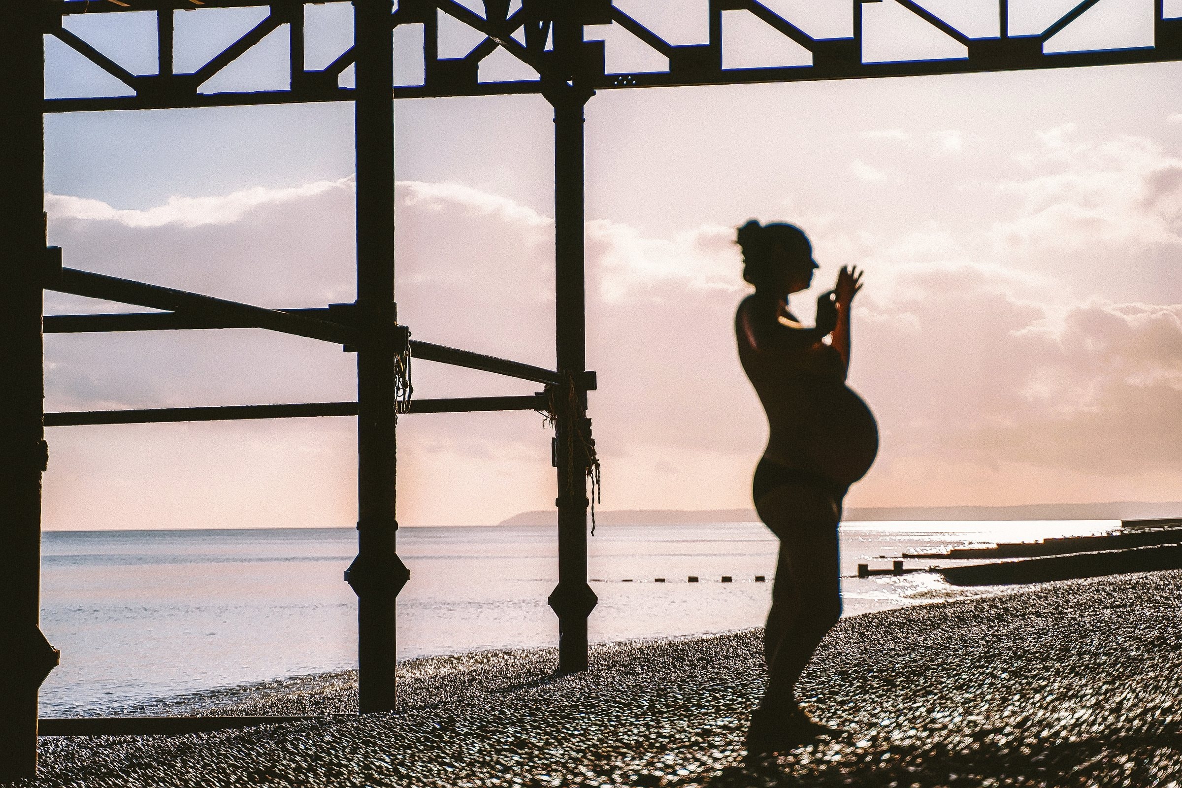 Solene silhouetted beneath the pier at sunset