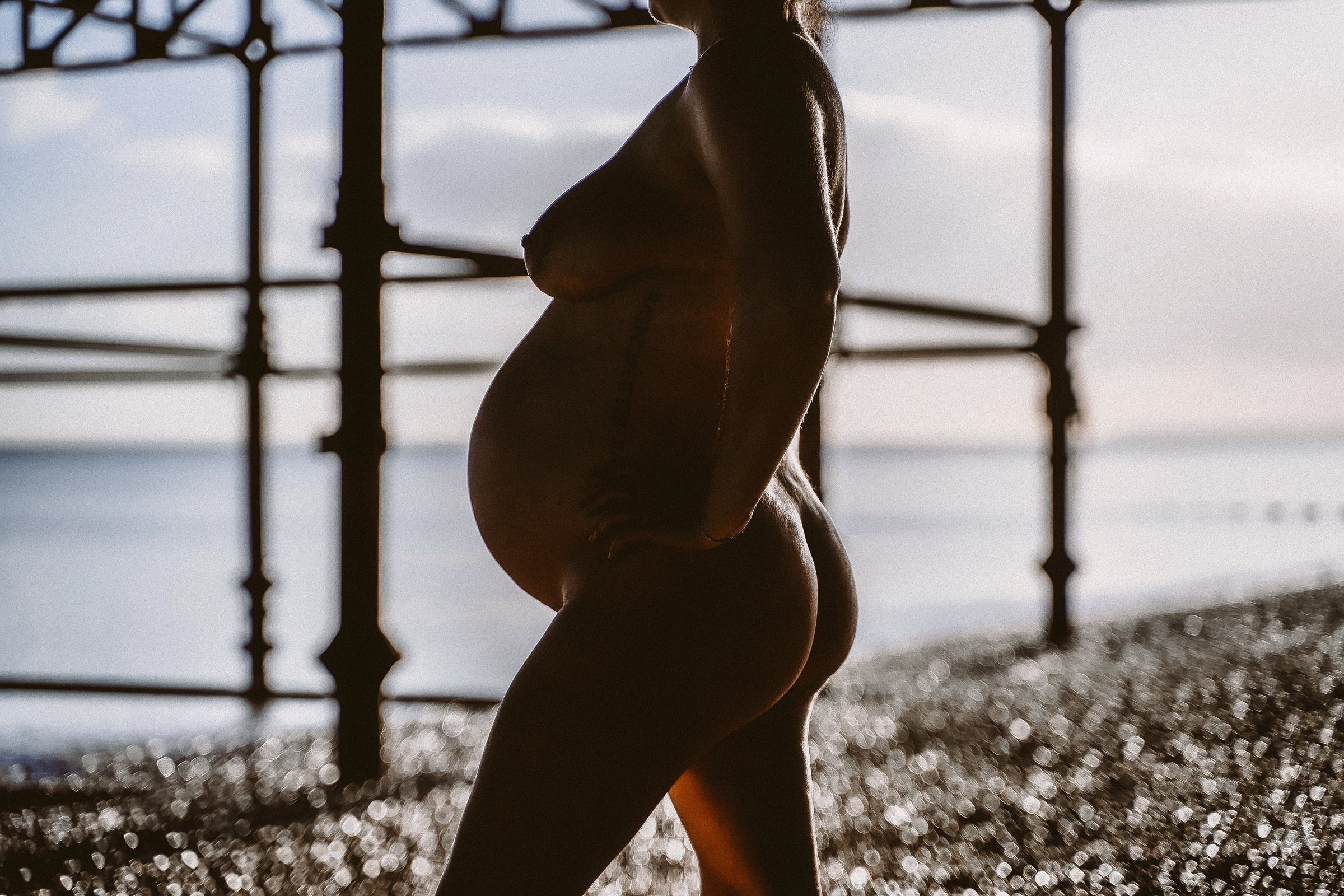 Solene arching beneath the pier in a strong maternity portrait