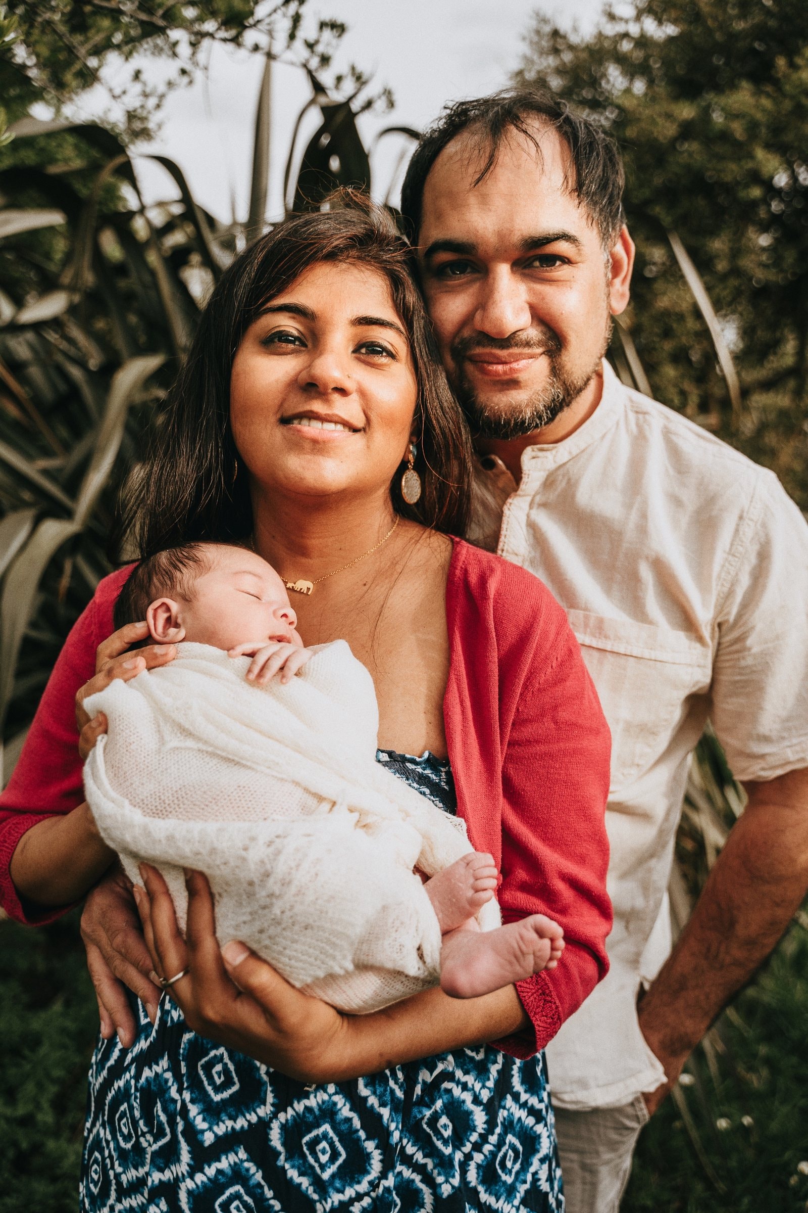 Amaya cradled between her parents in the garden