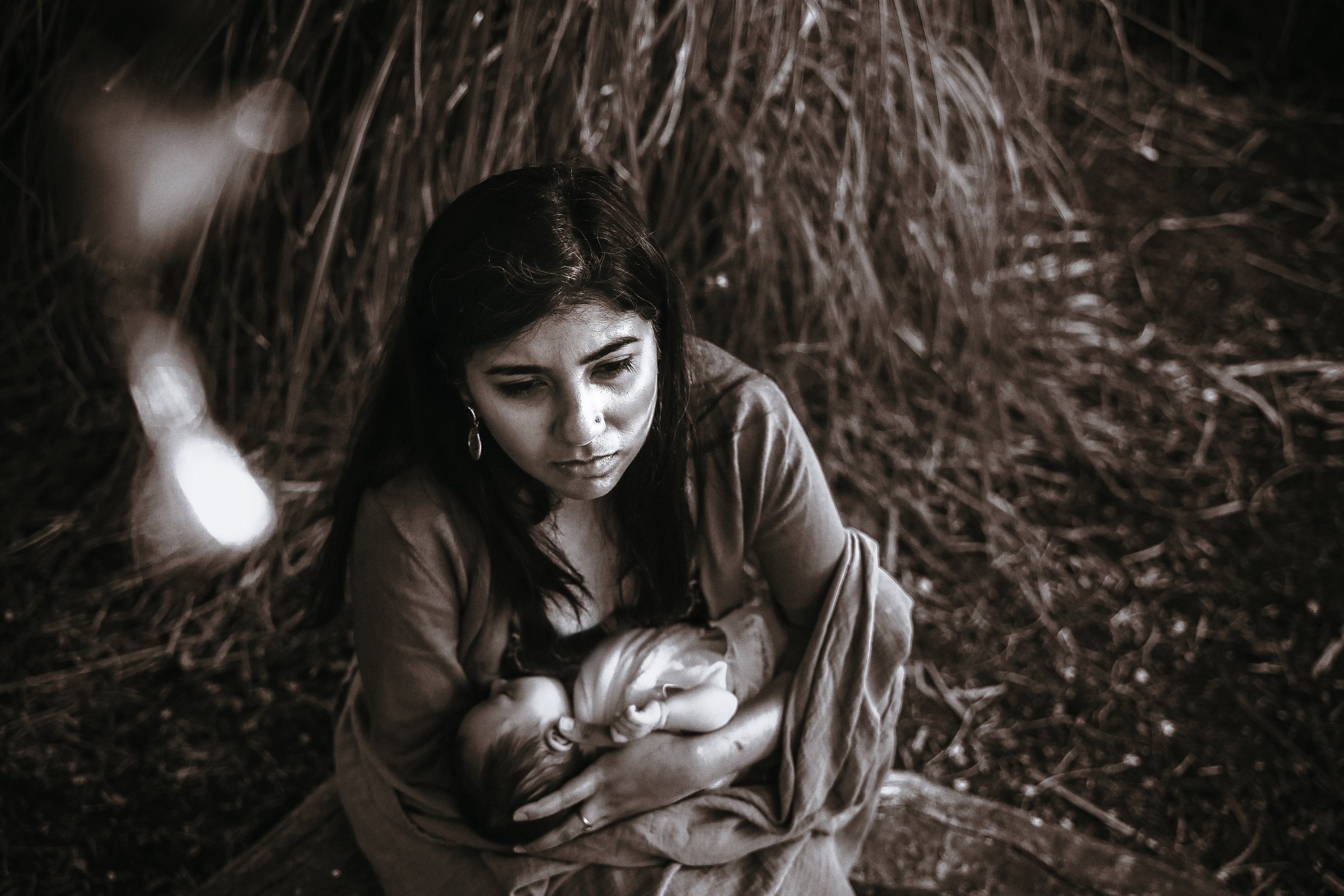 Amaya breastfeeding in her mother’s arms beneath tall grasses