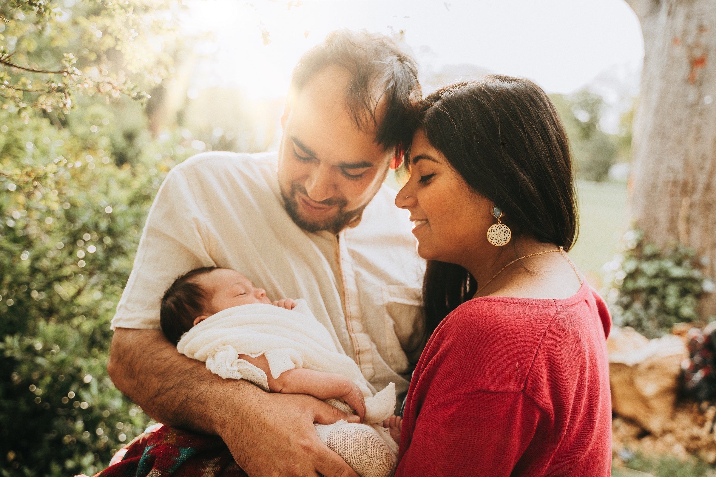Amaya held by her parents in soft afternoon light