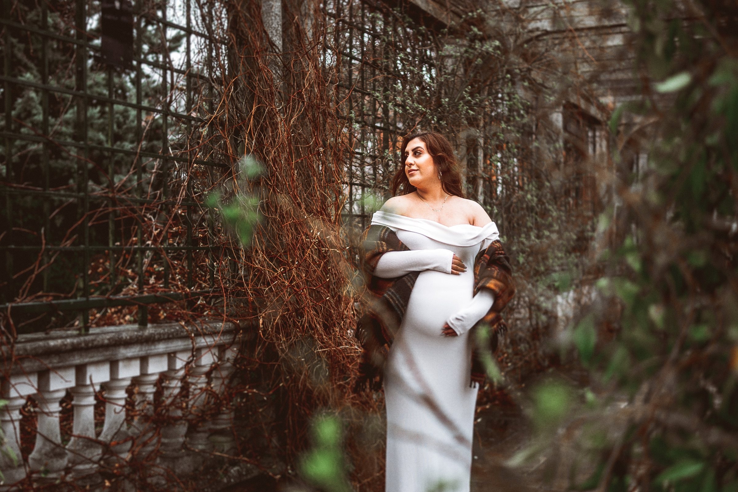 Noor in white among the trees while pregnant