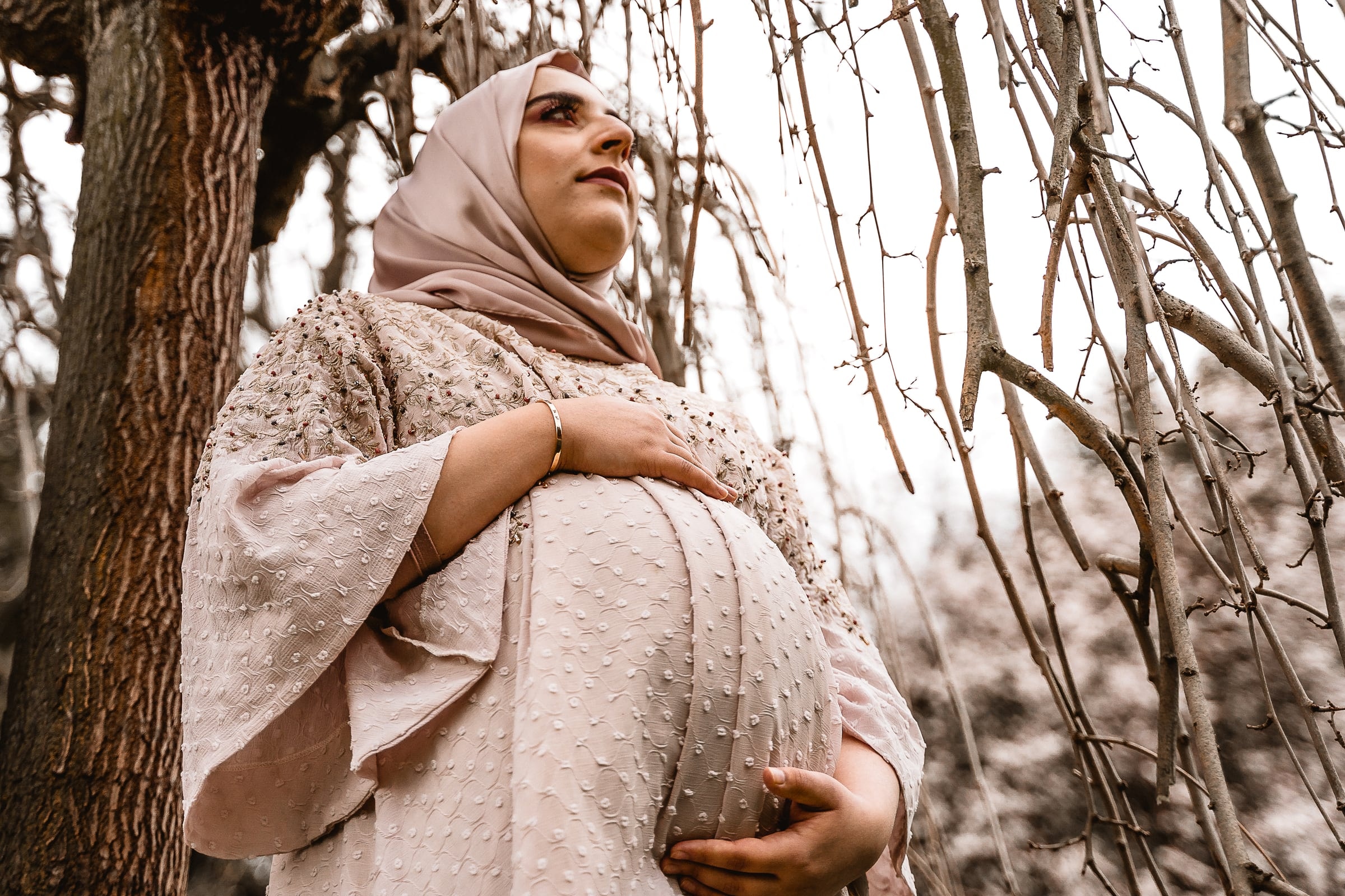 Pregnant woman in an embroidered dress among trees