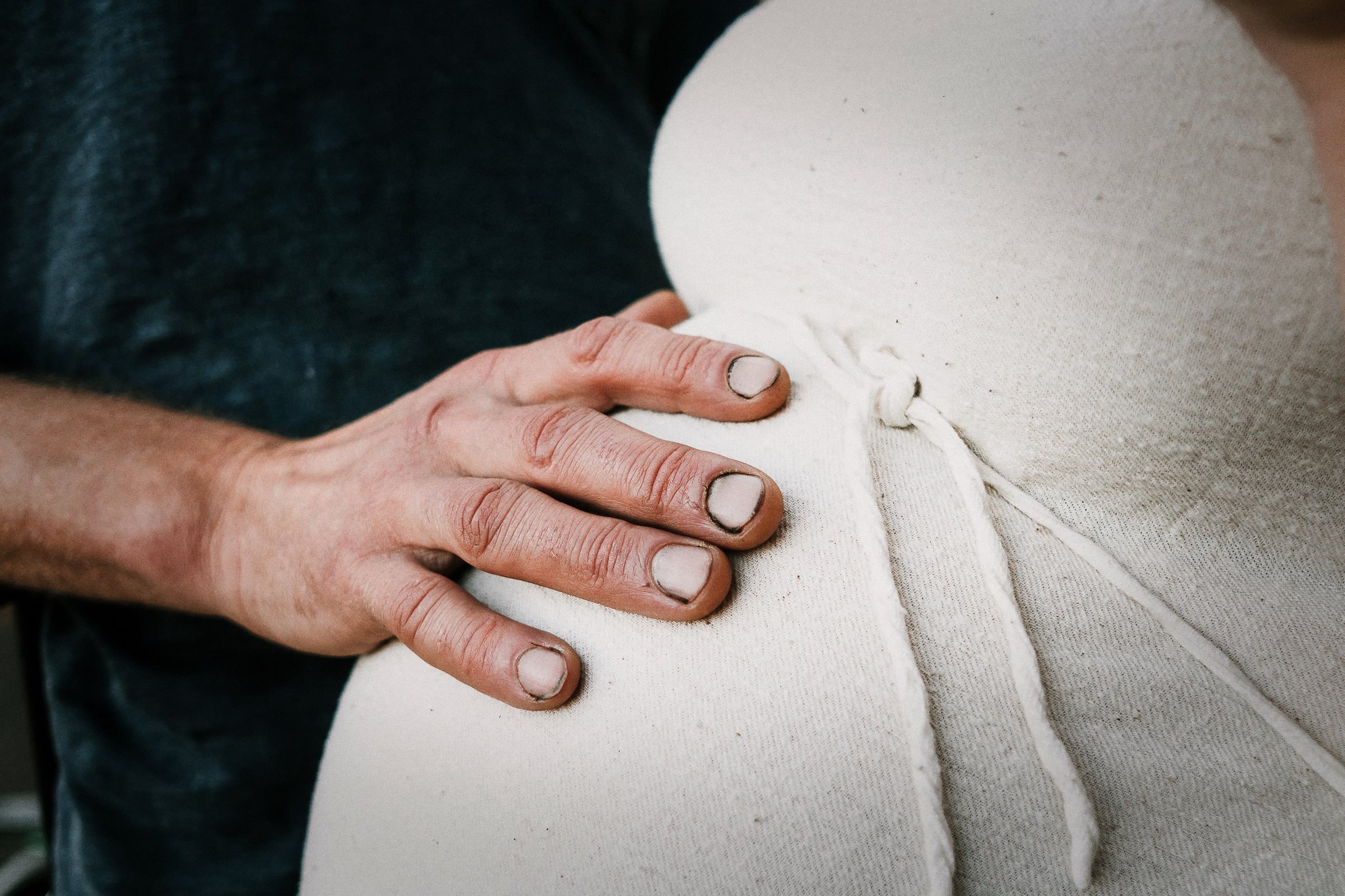 A close detail of a pregnant belly beneath a resting hand
