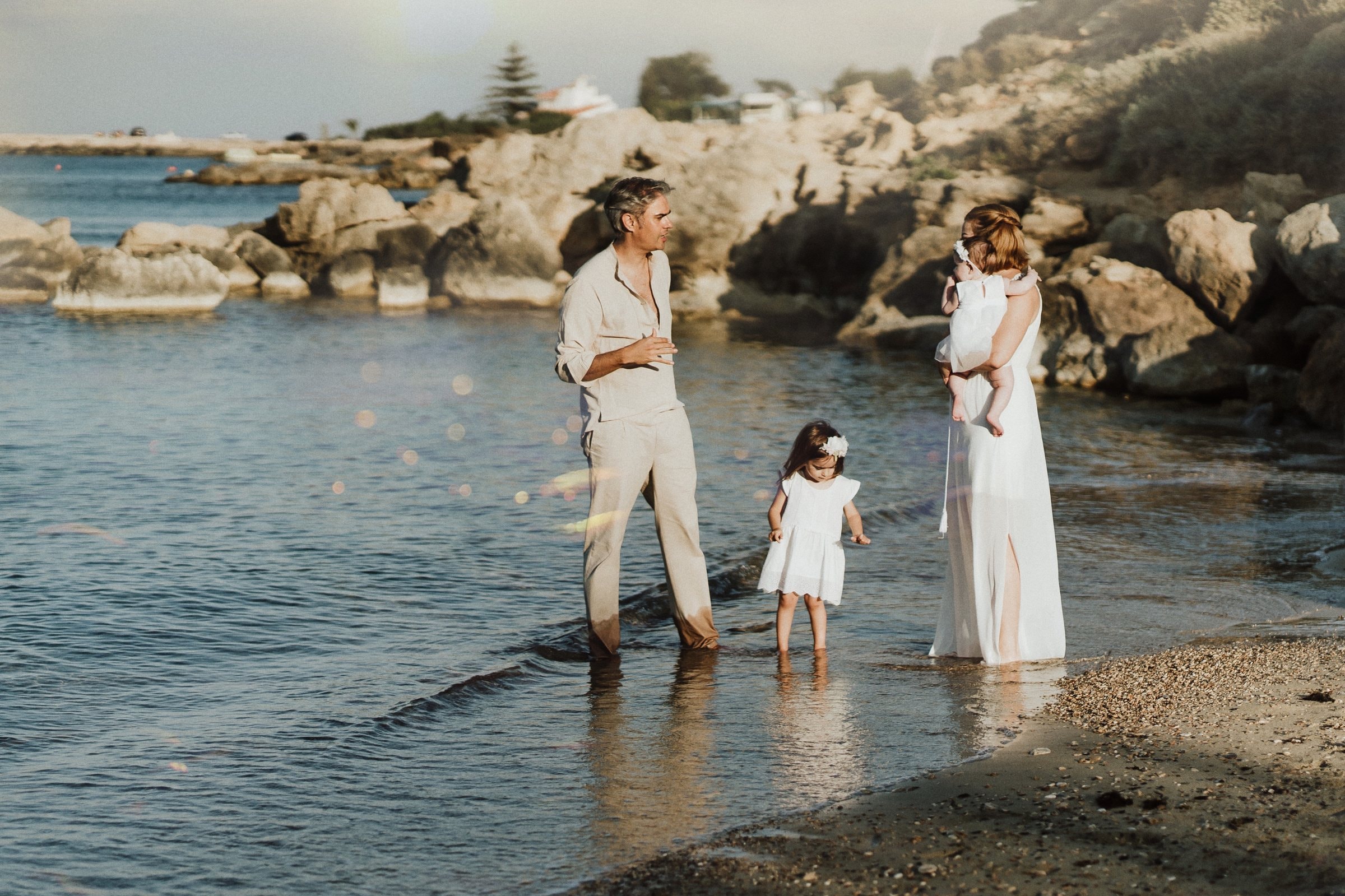 The family standing together on the rocky shoreline