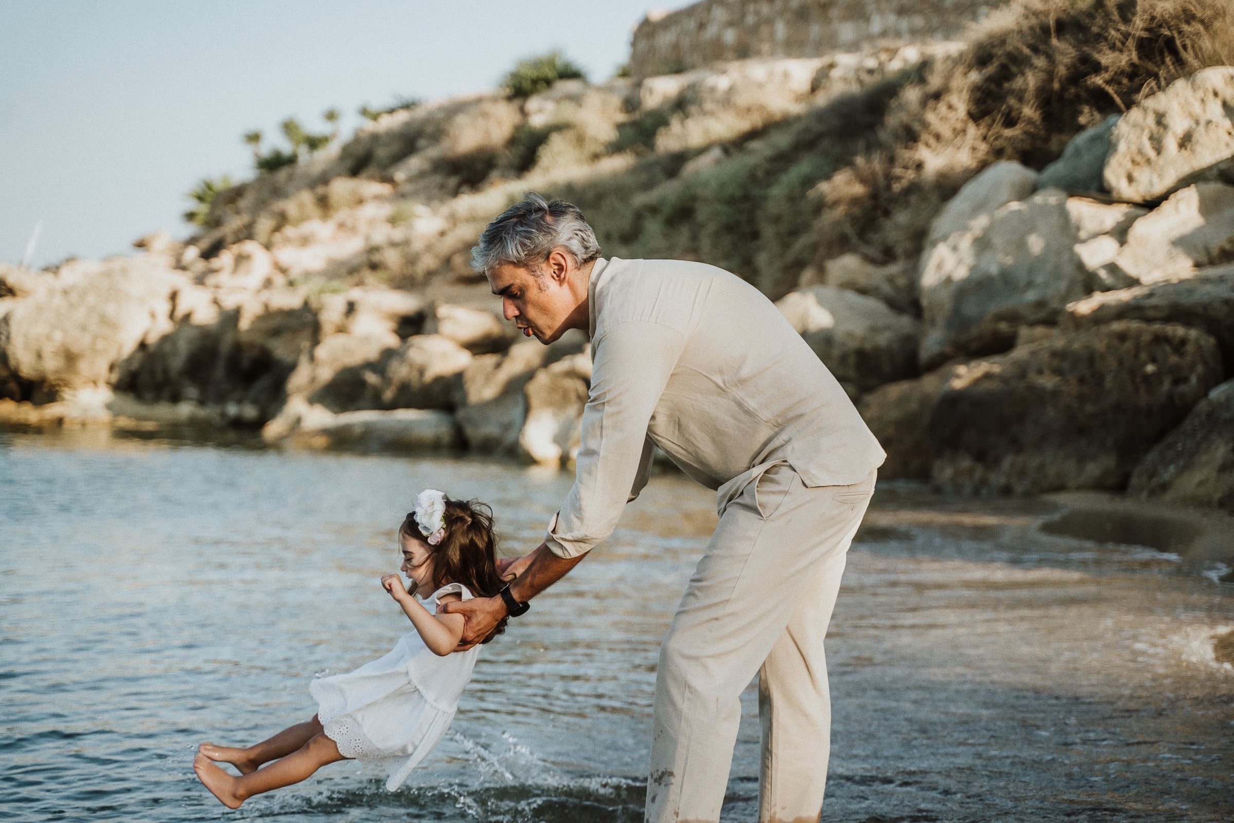 A father swinging his daughter over the shallows