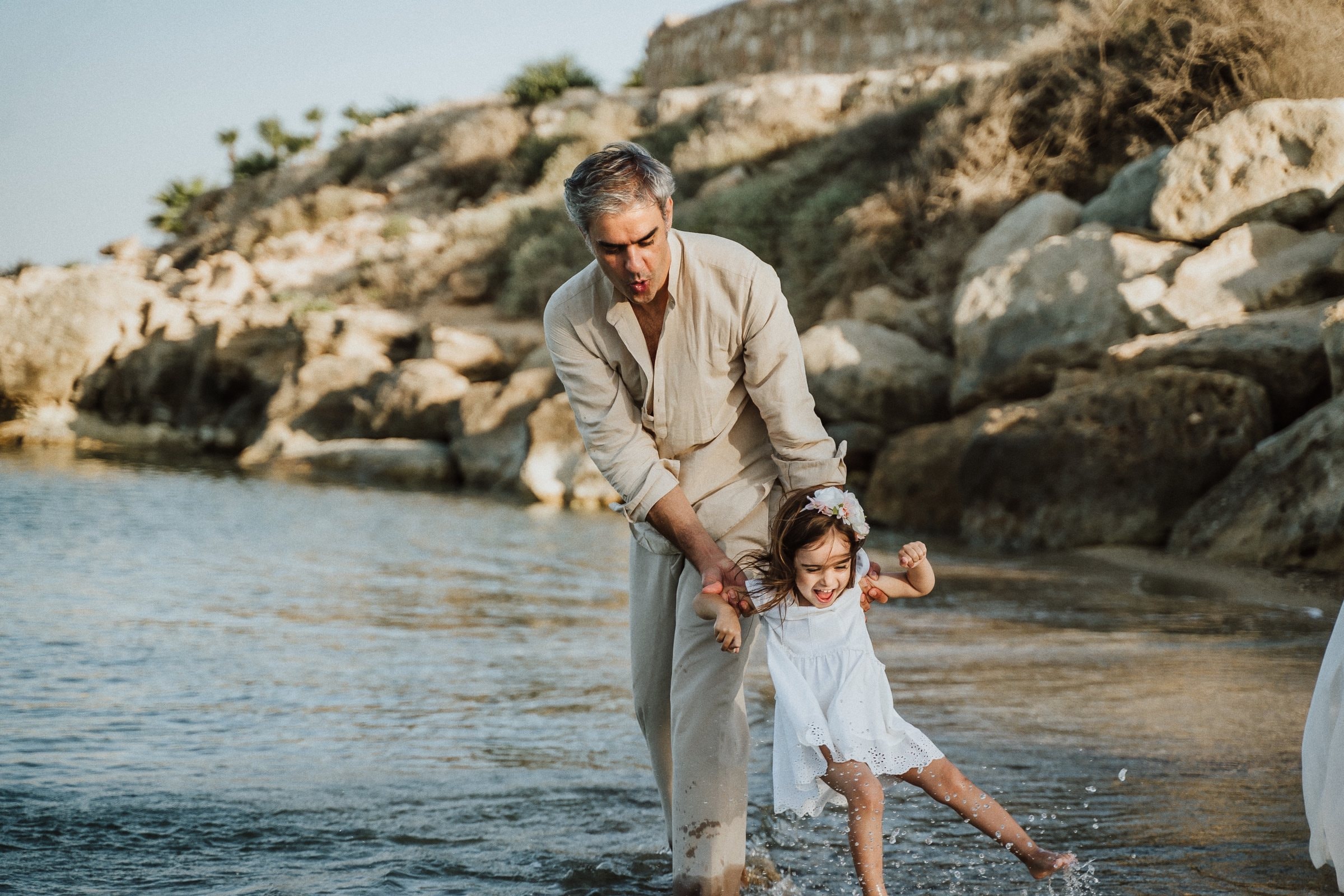 A father playing with his daughter beside the rocky shore