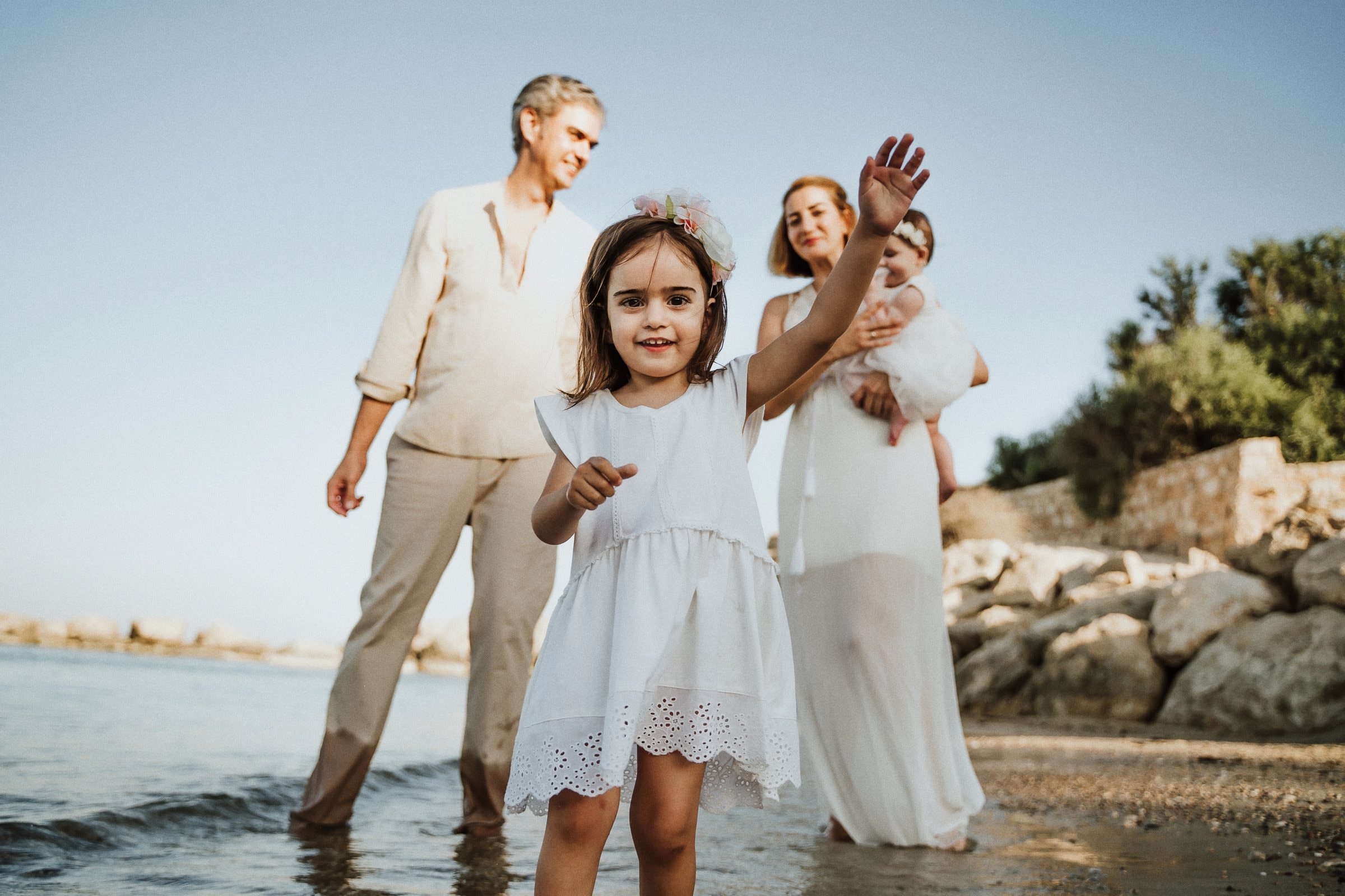 A child running between her parents on the shore