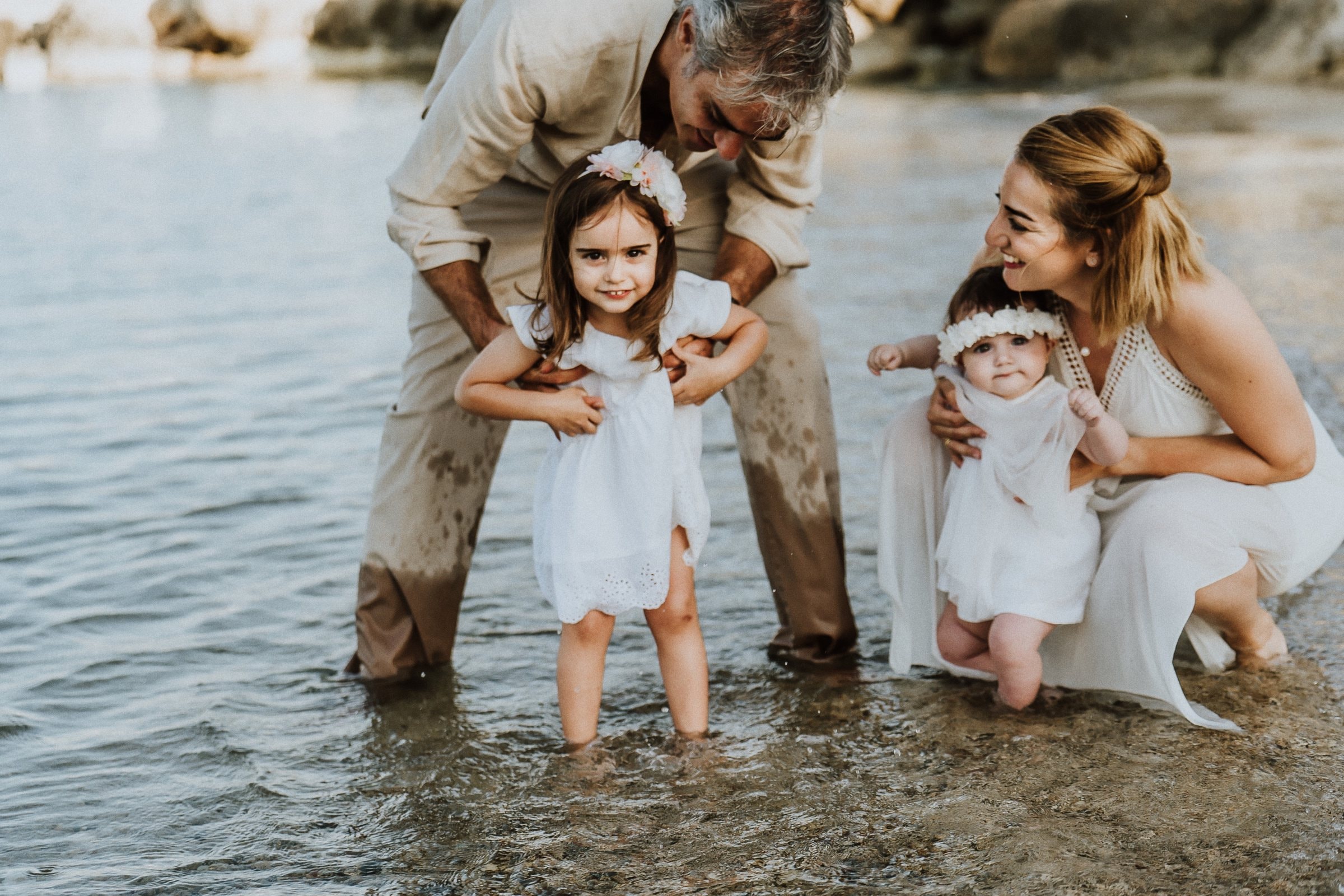 Parents crouching beside their children in the shallows