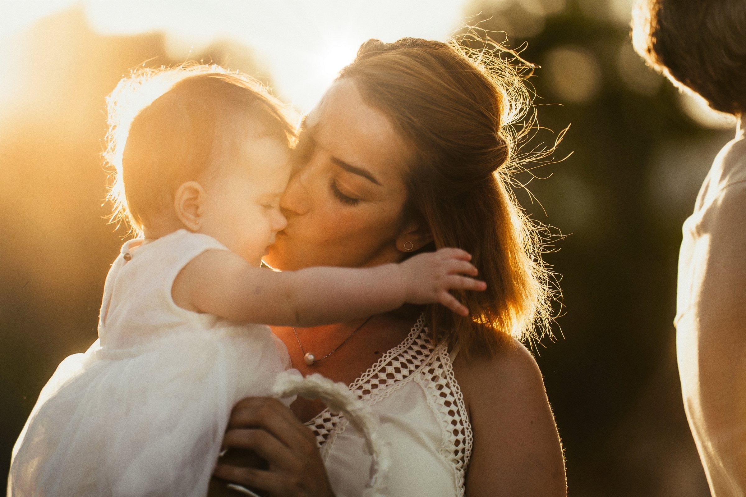 Tasha kissing her baby in the amber evening light