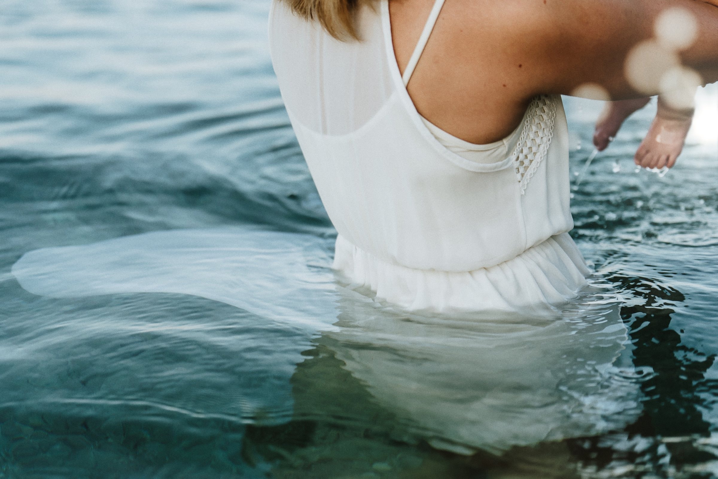 Tasha carrying her baby through sunlit water