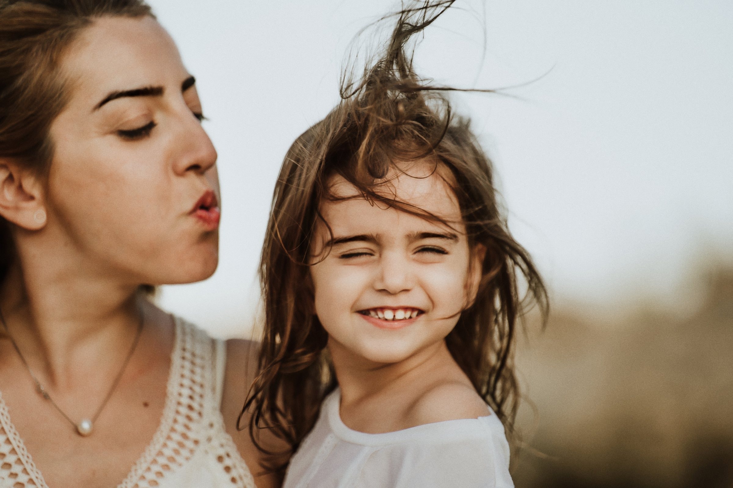 A laughing child framed by her mother at the beach