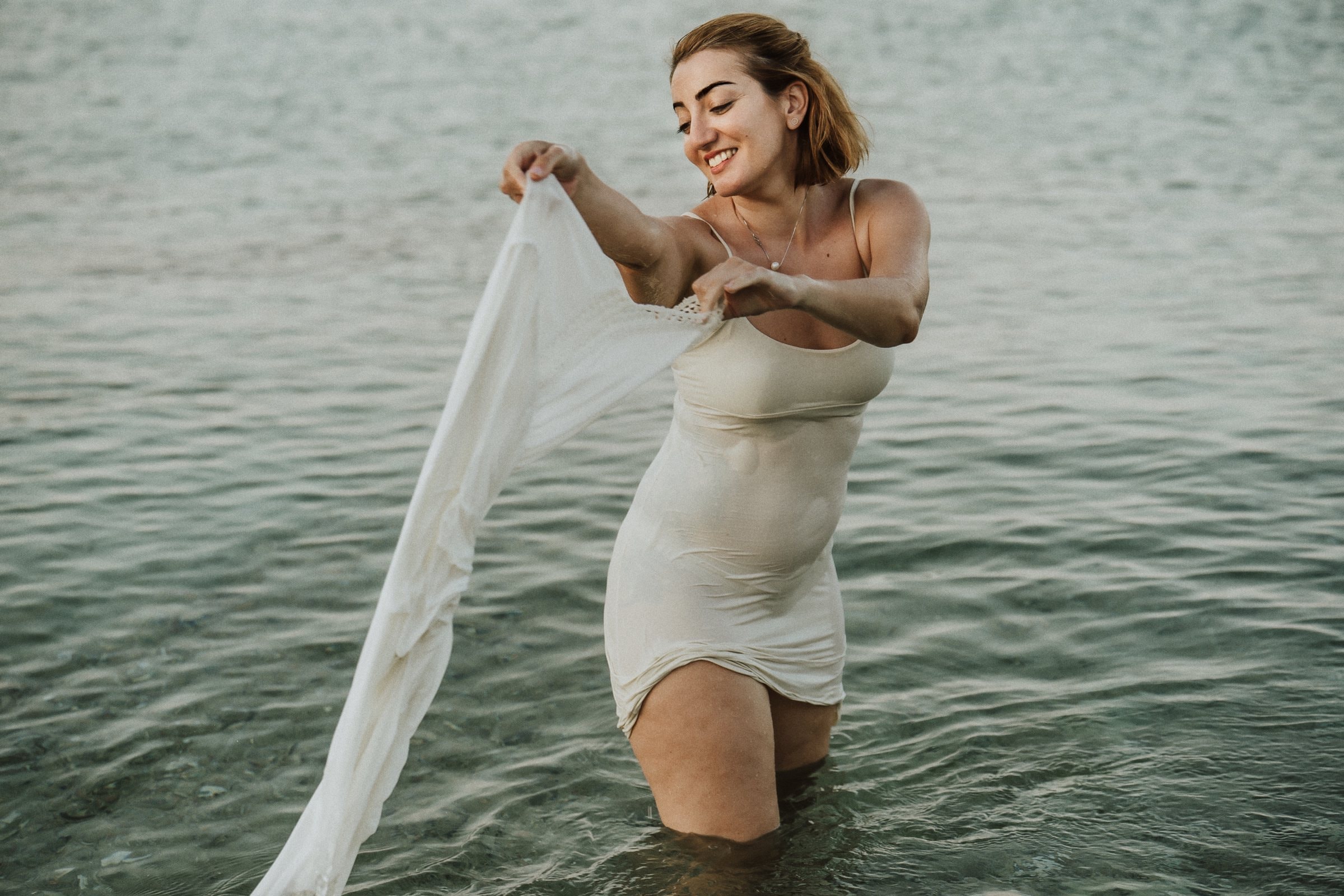 Tasha wading through the sea in a white dress